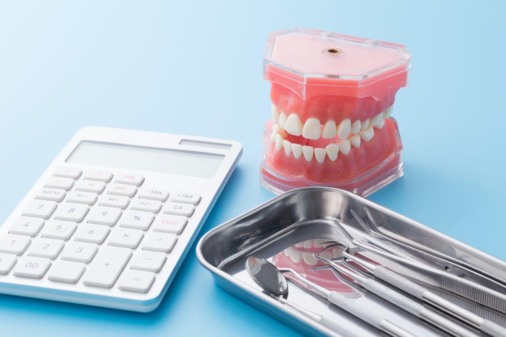 電卓と歯の模型と歯の治療器具